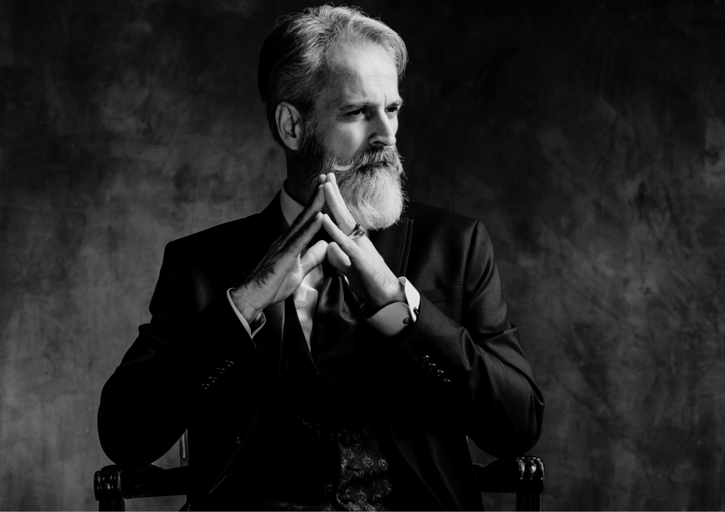 Homme pensif avec une barbe blanche, vêtu d’un costume, symbolisant la sagesse et le développement personnel