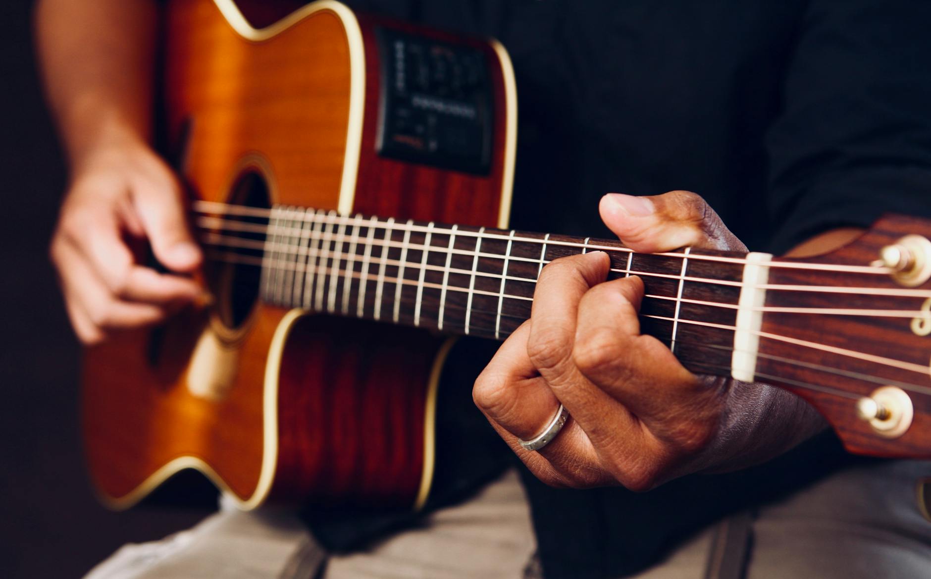 Une personne jouant de la guitare. Symbolisant une activité créative et un apprentissage d'une nouvelle compétence qui libère de manière saine de la dopamine.