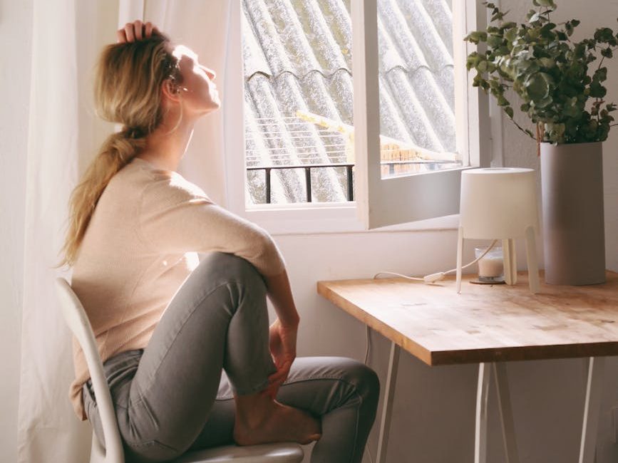 Une femme qui regarde par la fenêtre ouverte 
